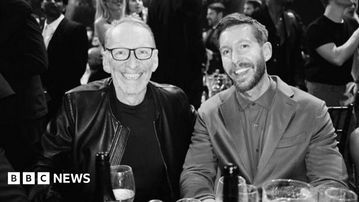 A black and white photo of DJ Calvin Harris in a suit with a T-shirt underneath alongside Mike Pickering in a leather jacket with dark glasses and grey receding hair