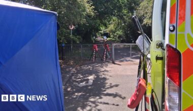 A police tent and van parked near an alleyway where floodlights have been set up.