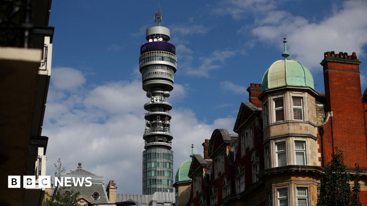 Tall slender, glass, BT Tower rises from between residential buildings