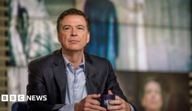 James Comey wears a suit and holds a mug on the set of NBC News' Meet the Press.