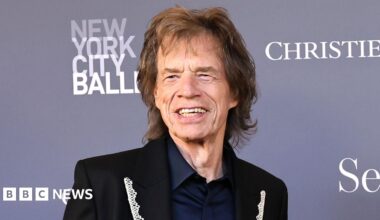 Mid-shot of Sir Mick Jagger, wearing a lace lapelled suit jacket