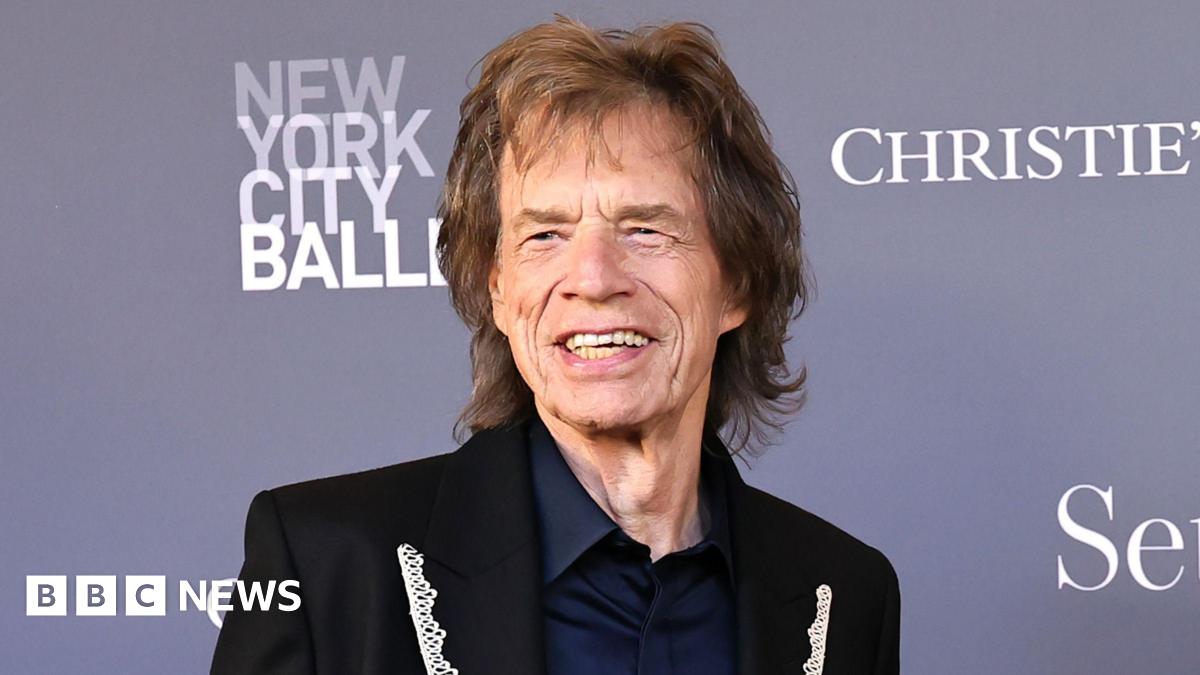 Mid-shot of Sir Mick Jagger, wearing a lace lapelled suit jacket