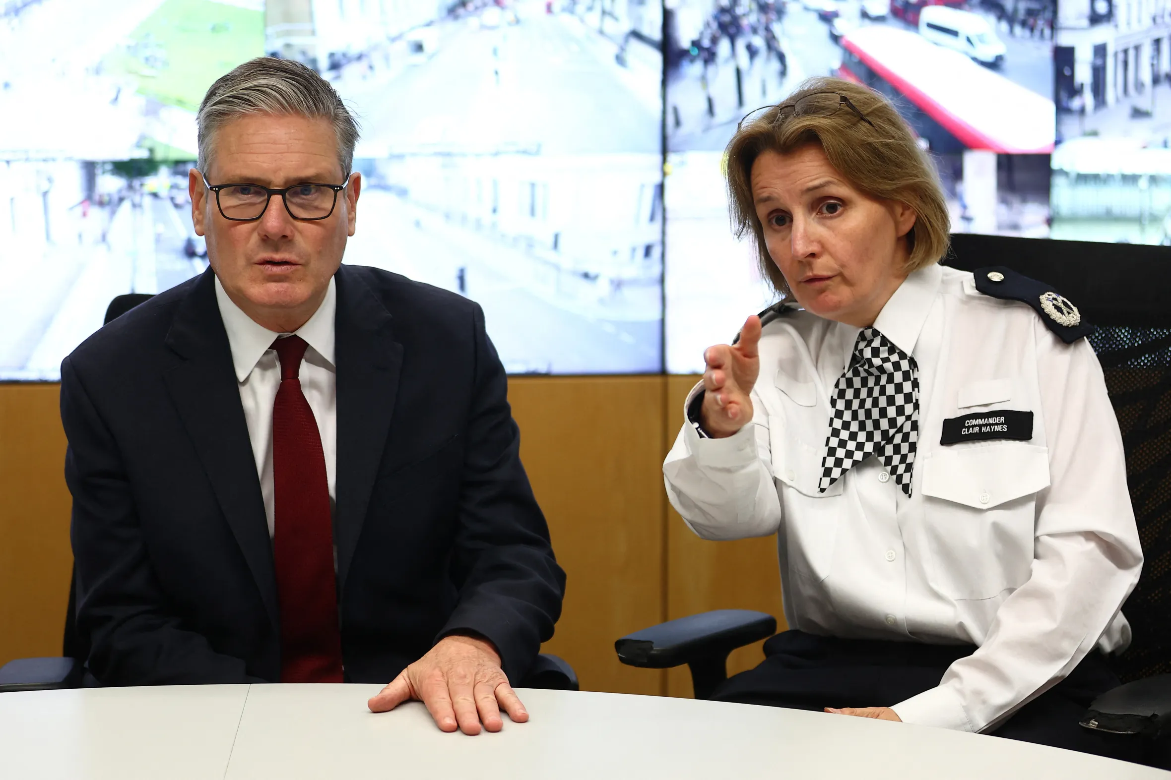 Britain's Prime Minister Keir Starmer and Commander Clair Haynes discuss operational planning in front of CCTV screens.