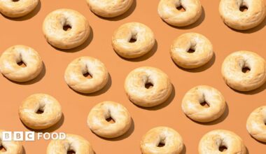 Cut out of bagels lined up in diagonal rows on a pale orange background.