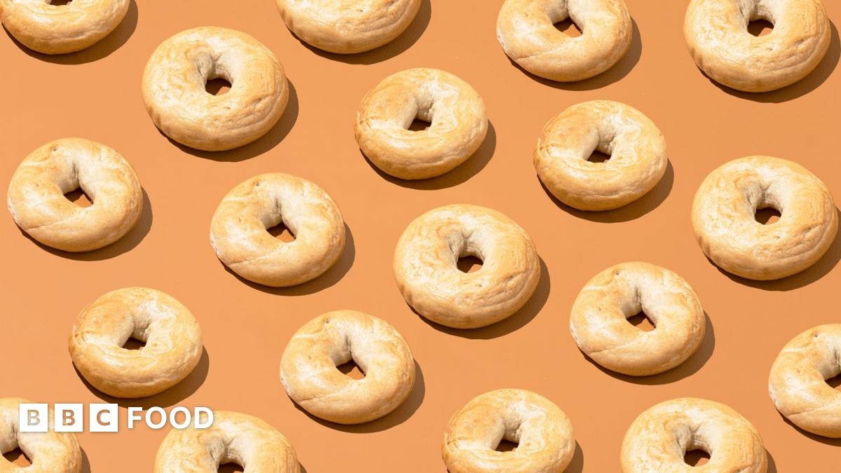 Cut out of bagels lined up in diagonal rows on a pale orange background.