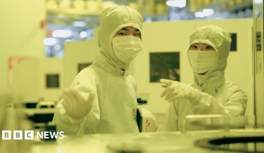 Employees of SK Hynix in discussion while dressed in white protective gear in a clean room
