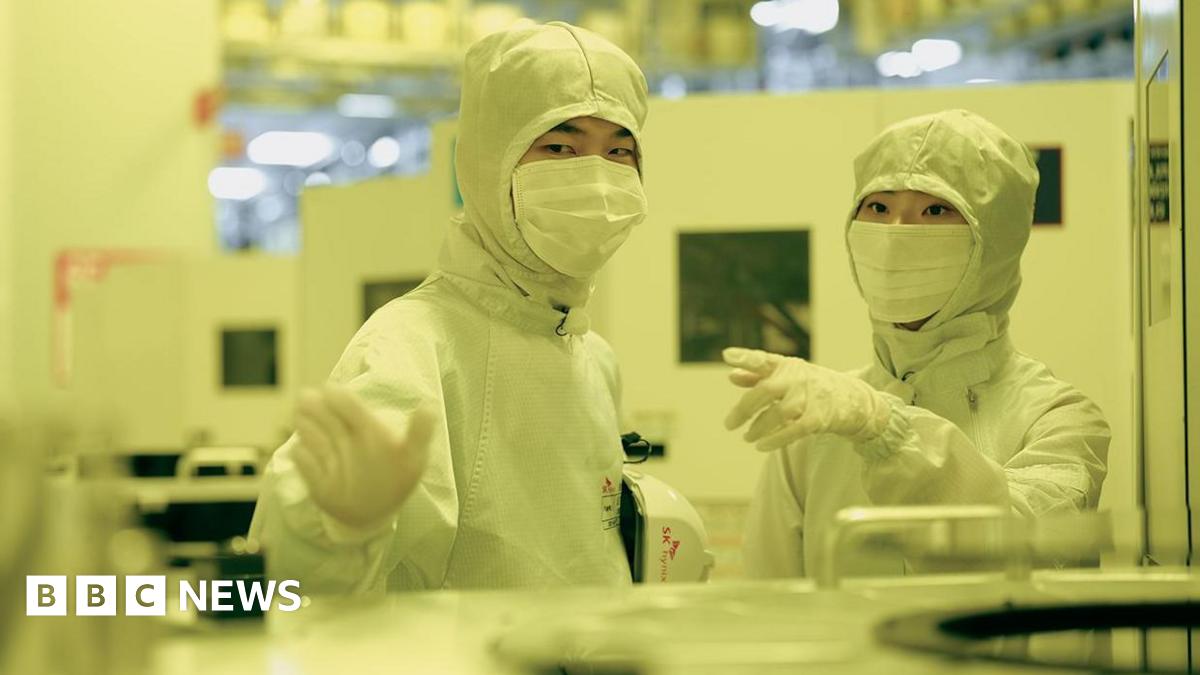 Employees of SK Hynix in discussion while dressed in white protective gear in a clean room