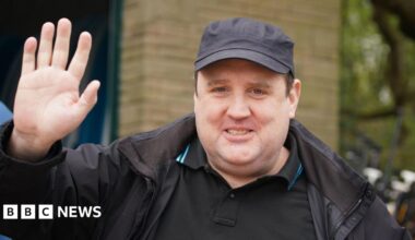 Peter Kay wears a cap and looks towards the camera