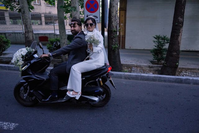 A bride and groom ride on their motorbike in northern Tehran