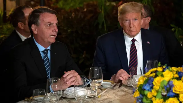 Trump sits at a table with Jair Bolsonaro