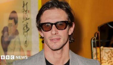 Jake Hall wearing a grey suit jacket and tinted glasses at the Entitled 1 launch at China Tang on March 12, 2026 in London