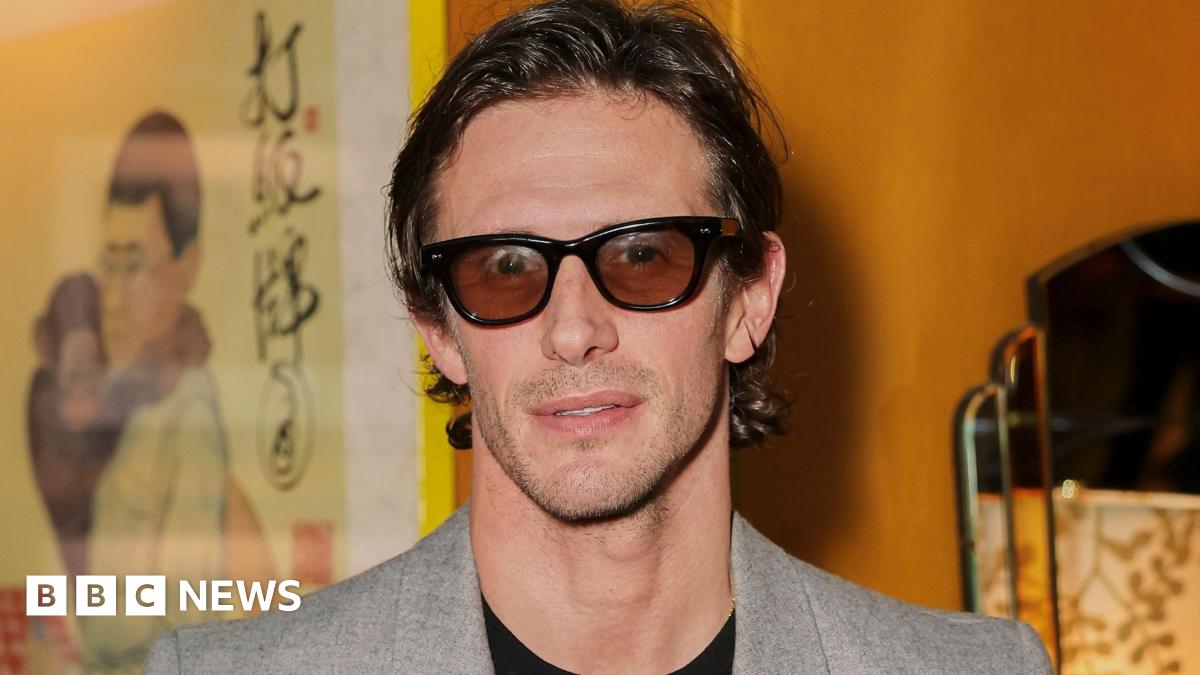 Jake Hall wearing a grey suit jacket and tinted glasses at the Entitled 1 launch at China Tang on March 12, 2026 in London