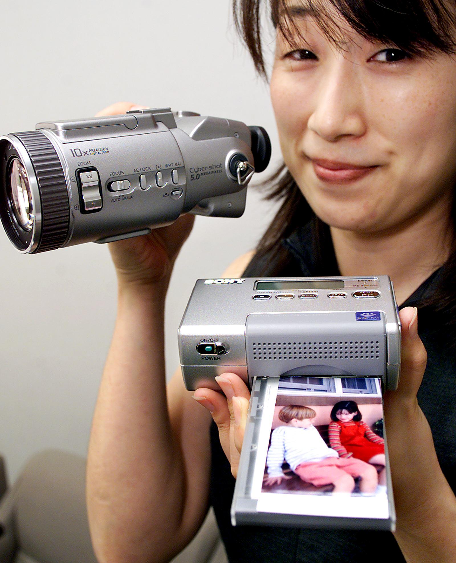 Saori Takahashi, an employee for Japanese electronics giant Sony, displays a palm-top-sized thermal printer, Mobile DigitalPhotoPrinter DPP-MP1, and digital camera (L), the Cybershot DSC-F707