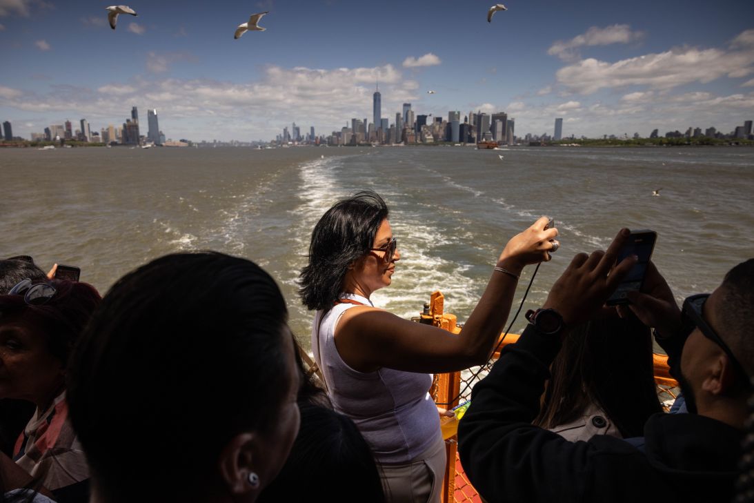 Tourists take pictures on the Staten Island Ferry in New York on May 10, 2025. Last year, four million fewer international tourists came to the United States.