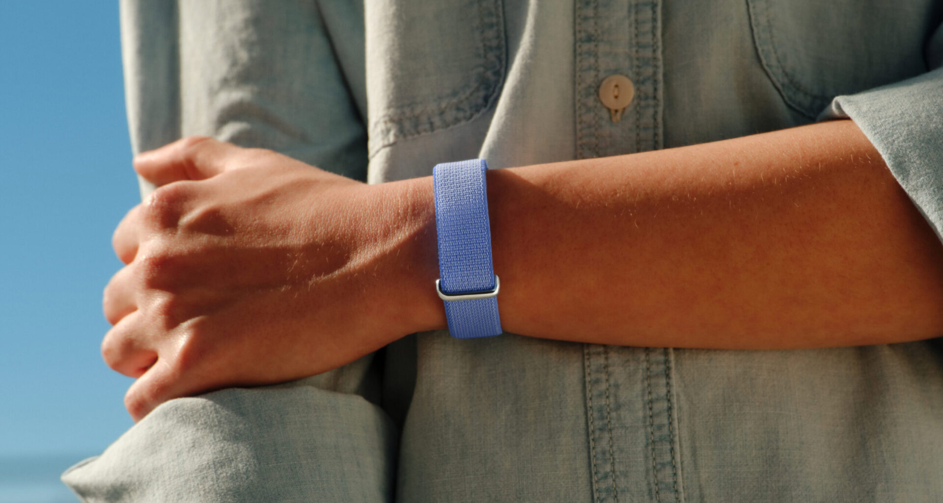 A lifestyle photo of someone wearing the Google Fitbit Air in its Lavender color.
