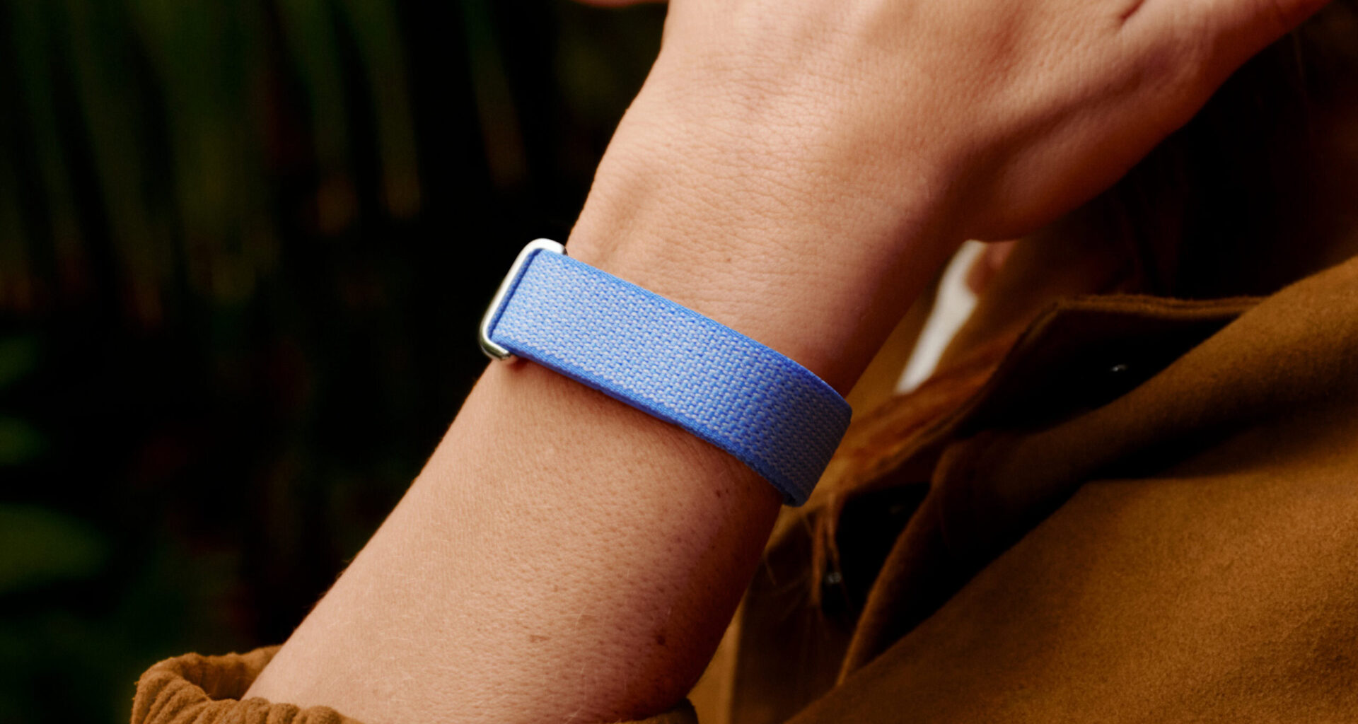 A lifestyle photo of someone wearing the Google Fitbit Air in its lavender band color.