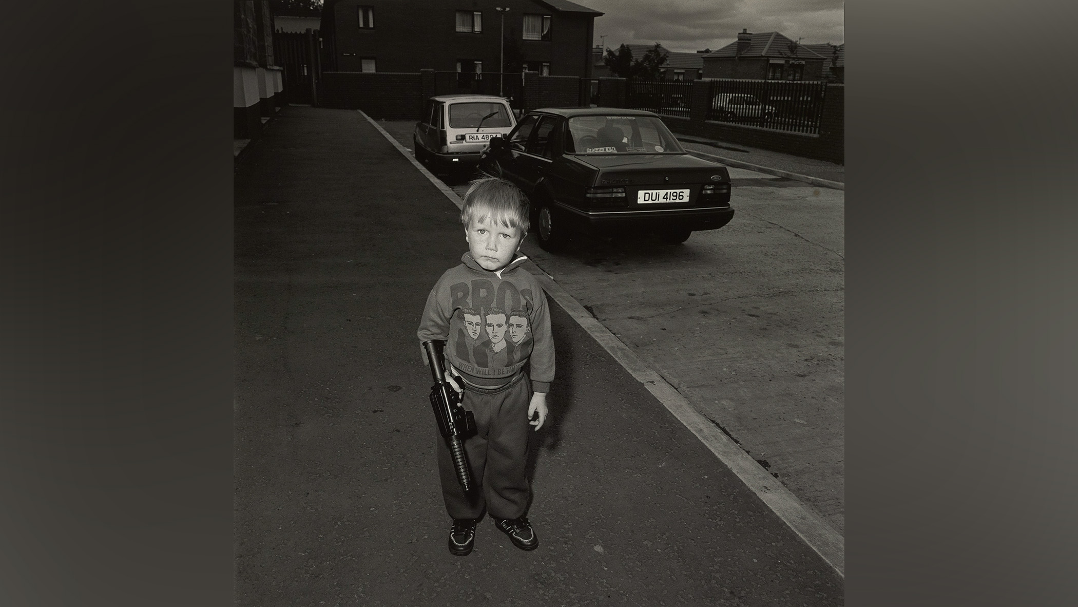 Boy in street holding toy gun.