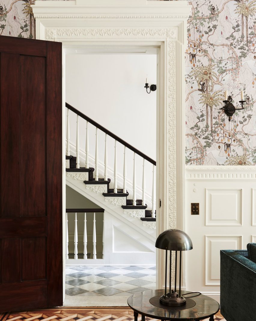 Doorway surrounded by intricate mouldings with a view to a staircase