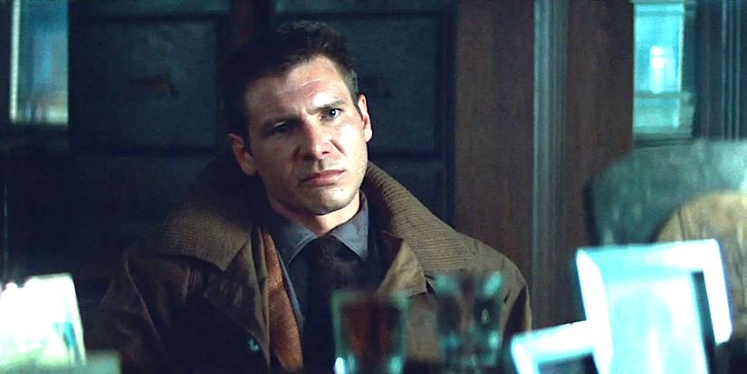 Harrison Ford as Deckard in Blade Runner seated in a grungy office looking across a desk with a slightly contemptuous expression