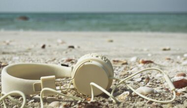 A pair of white headphones laid on the sand at the beach