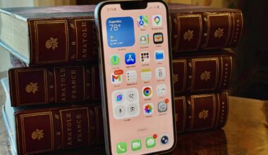 The iPhone 17E leans against leather-bound books