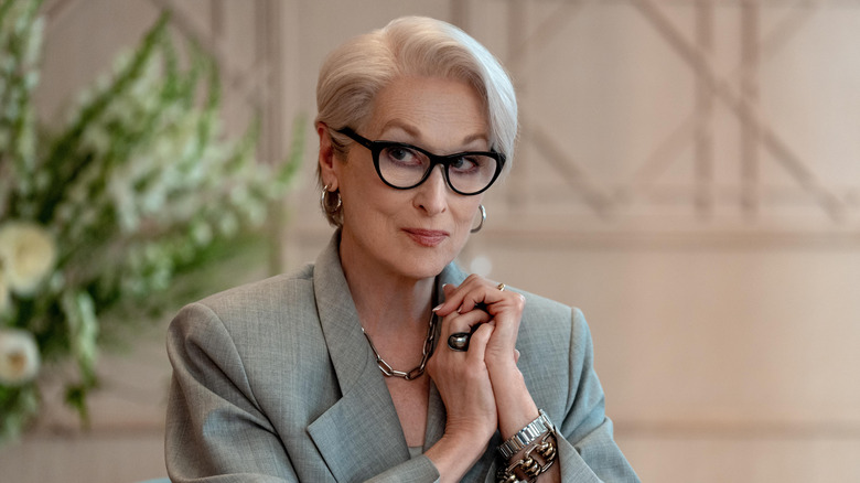 Meryl Streep as Miranda Priestly sitting at a table with her hands cupped together in The Devil Wears Prada 2