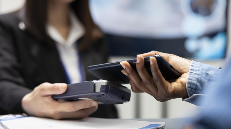 Close-up of hands completing tap to pay transaction with smartphone