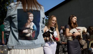 A candid street photograph by Janusz Jurek of women carrying dogs, with a denim jacket with a Leonardo Da Vinci painting of a woman holding an ermine