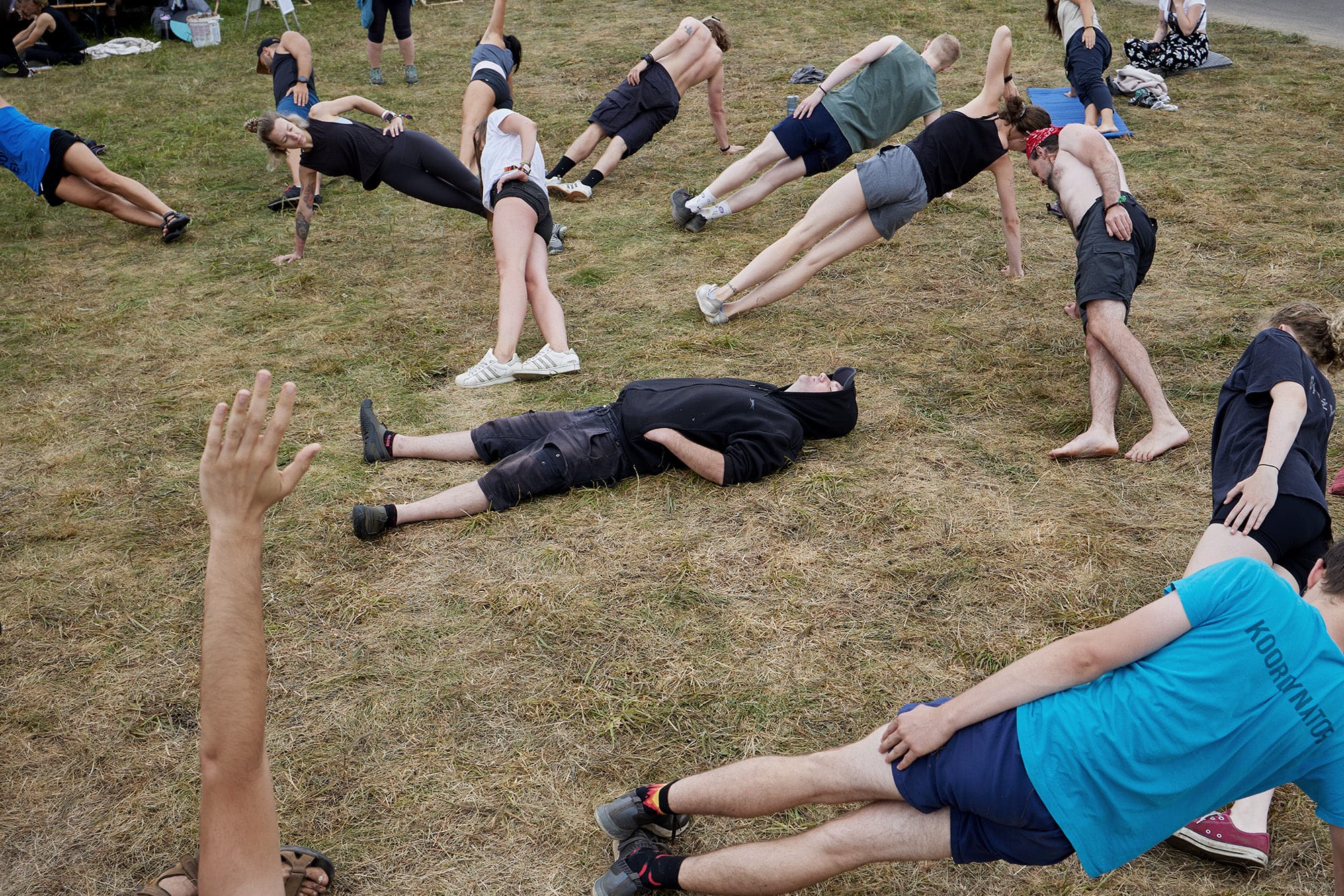 A candid street photograph by Janusz Jurek of people exercising in a park and one young man is just lying on the ground