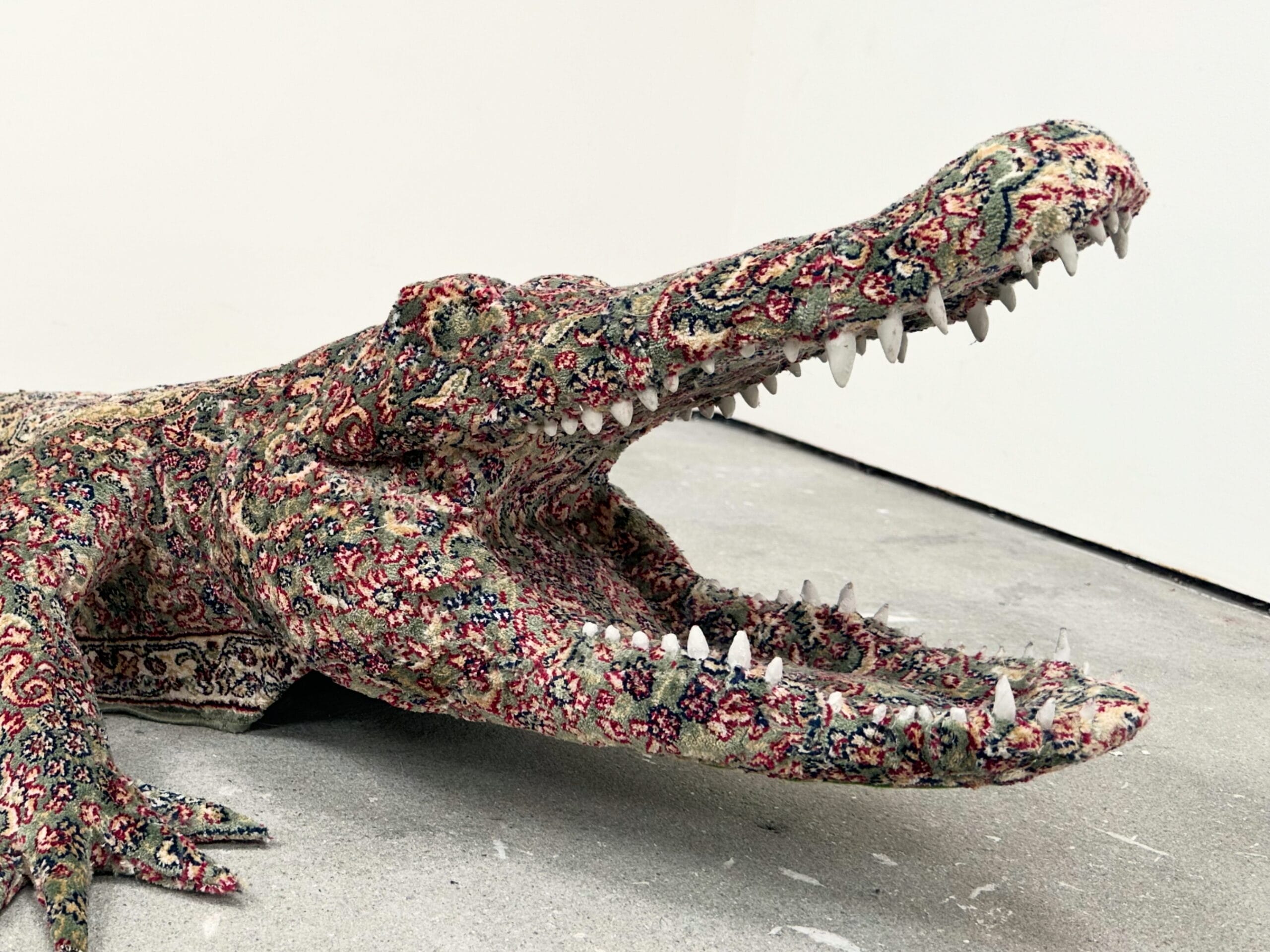 a detail of a floor sculpture by Debbie Lawson of an alligator coated in the pattern of an ornamental carpet