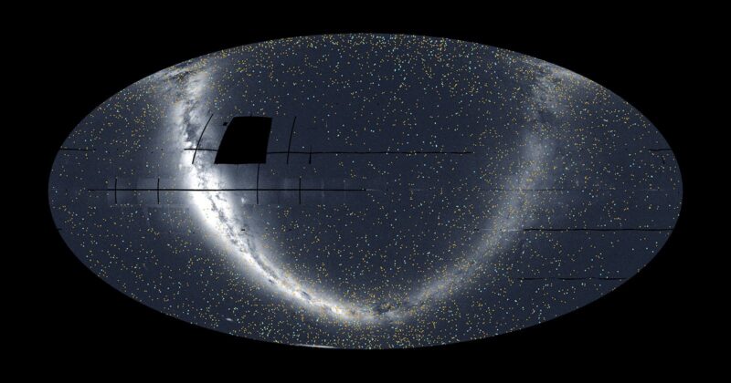 A wide, oval-shaped map of the night sky filled with tiny stars. A dense, bright arc of stars curves from the top left to the bottom right. A dark rectangular patch appears near the top left within the star field.