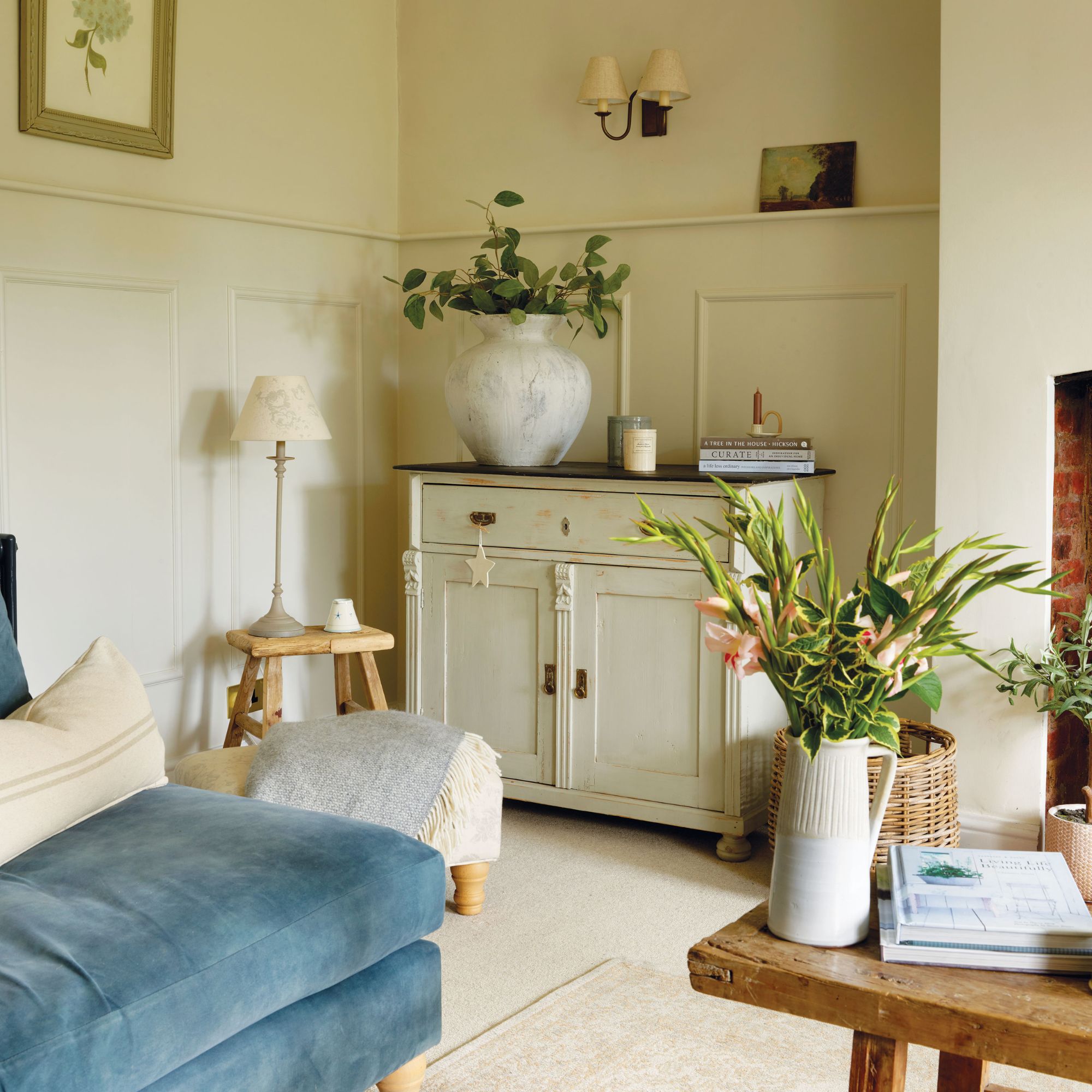 Living room in cottage with teal sofa and cream/beige decor and walls, with wooden coffee table