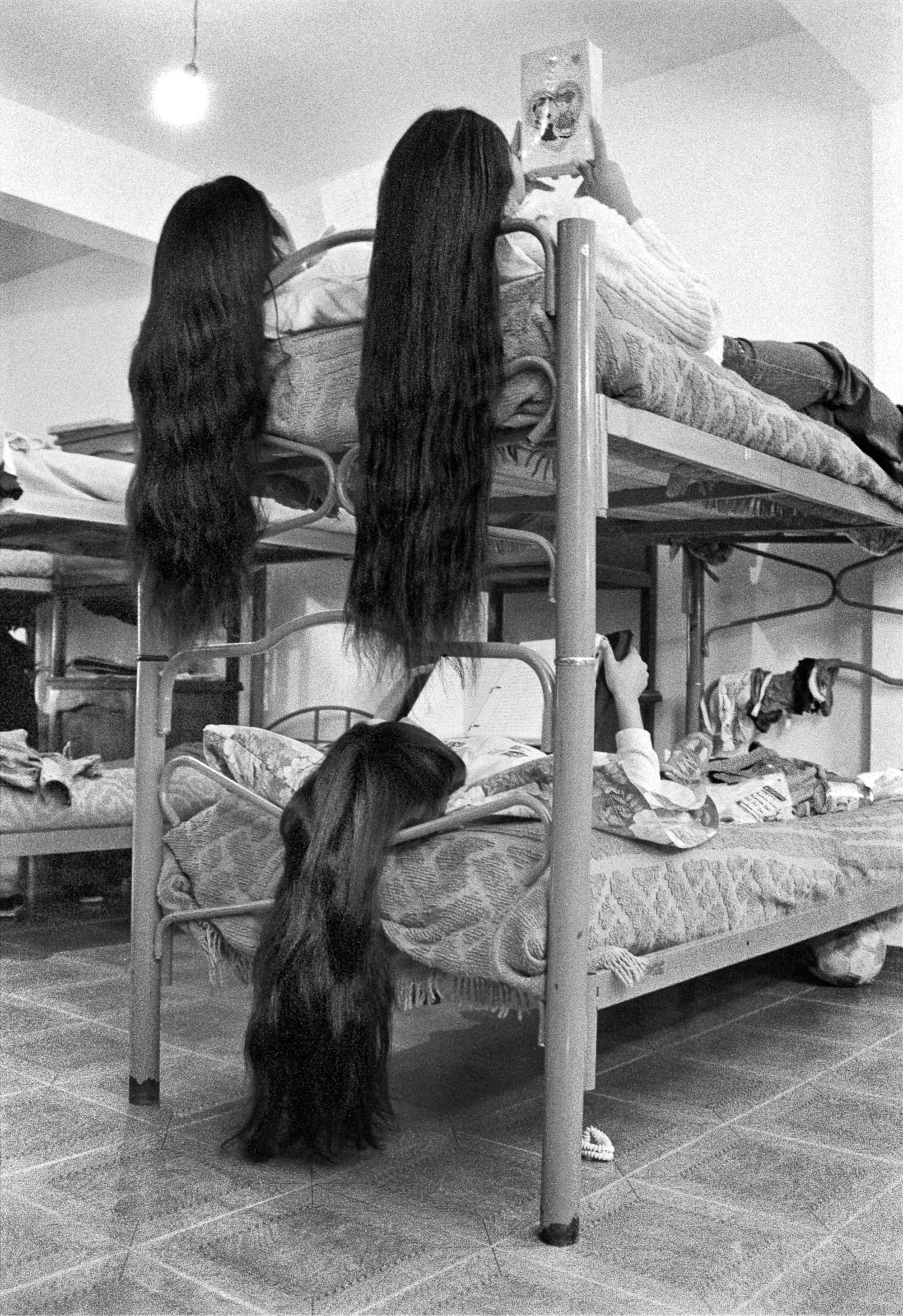 A trio of young women on a bunk bed with very long black hair draped over the edge of the bed