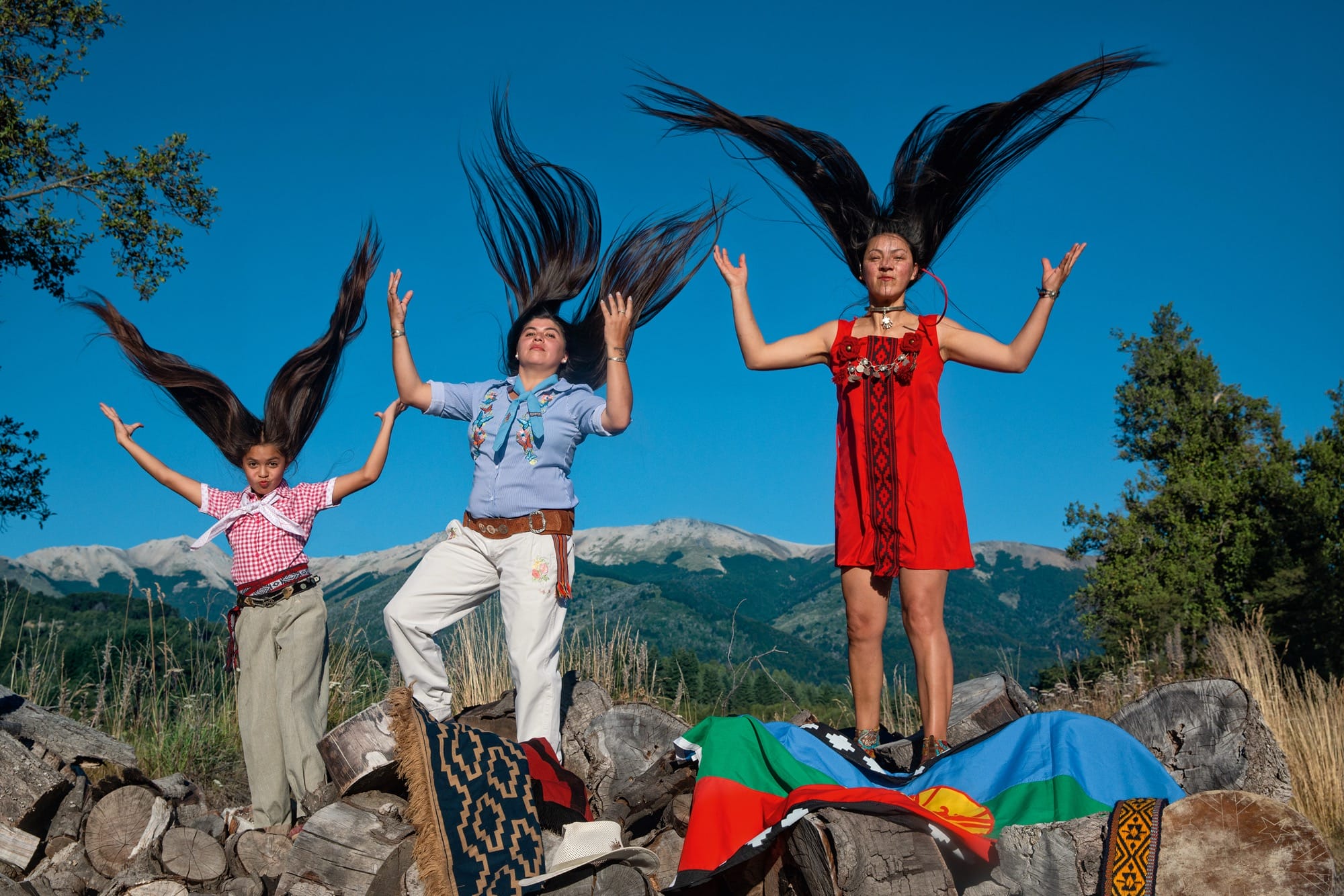 A group of young women with very long hair stand and throw their locks very high into the air