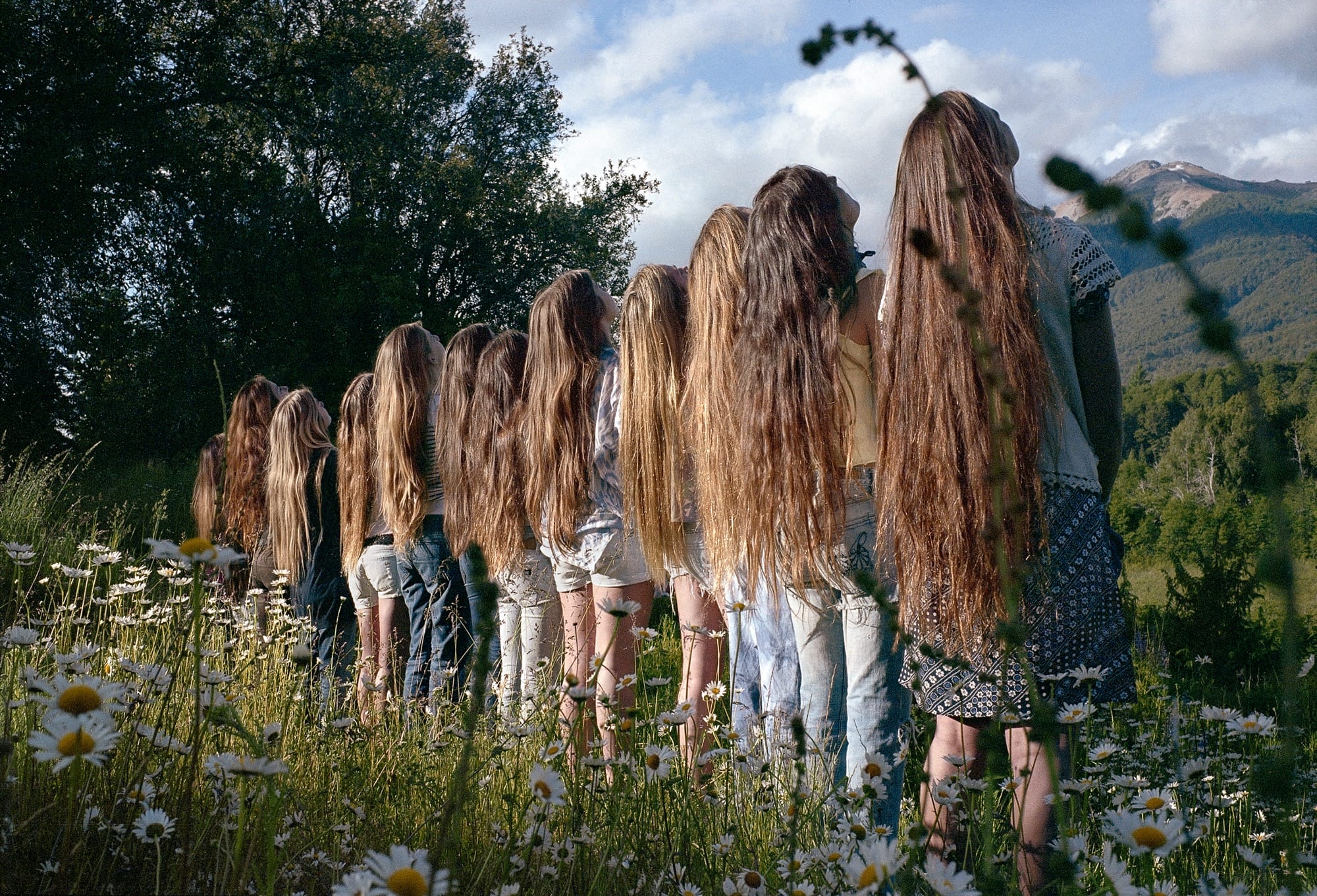A line of young women with very long hair, facing away from the camera