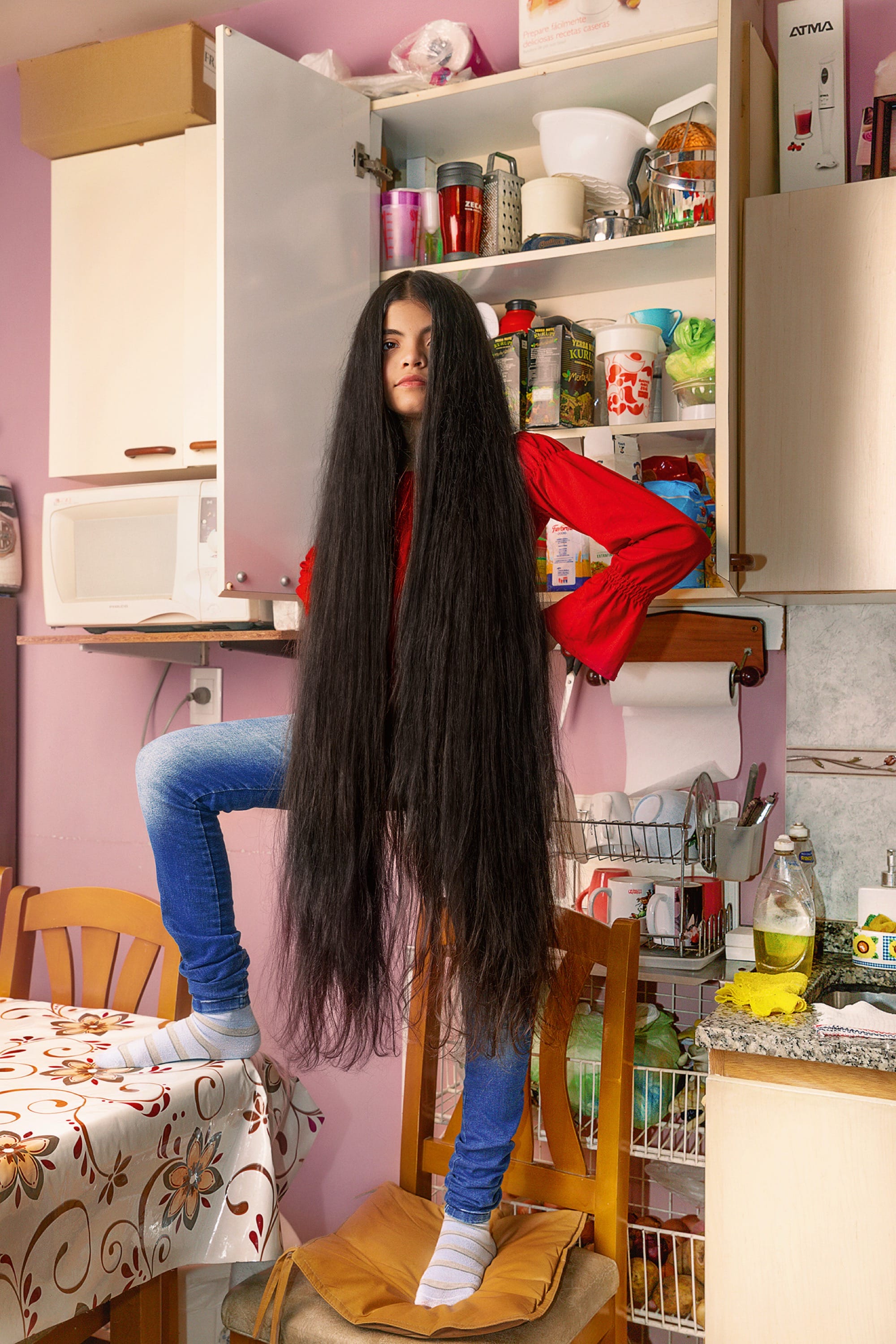A young woman with very long hair stands in her house