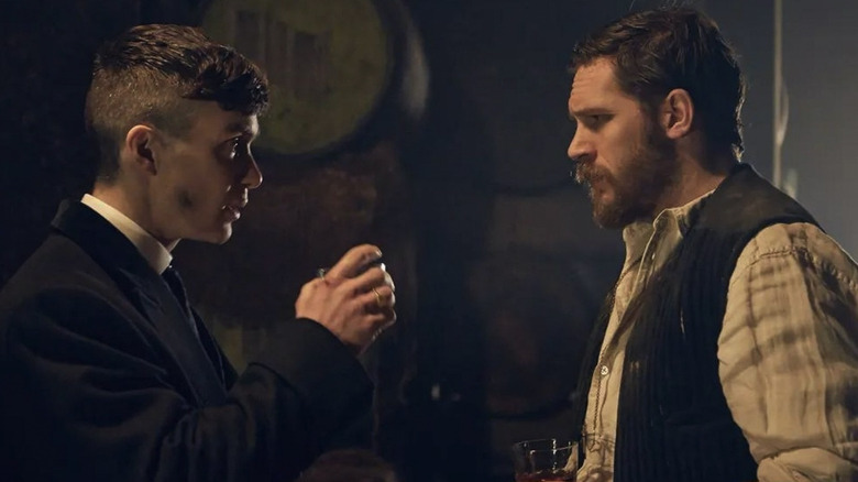 Alfie Solomons standing opposite Tommy Shelby, both with drinks in their hand, in Peaky Blinders