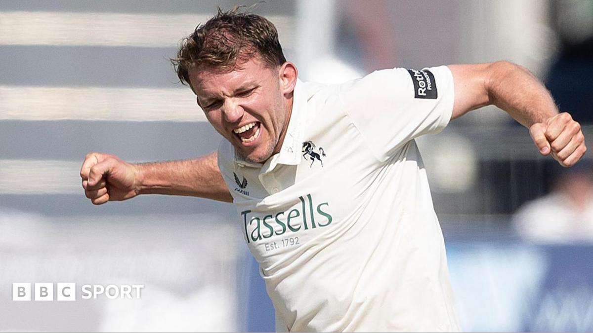 Matt Milnes in a white cricket shirt does a fist pump