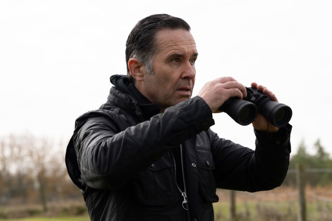 Graham looks ahead while holding binoculars in Emmerdale