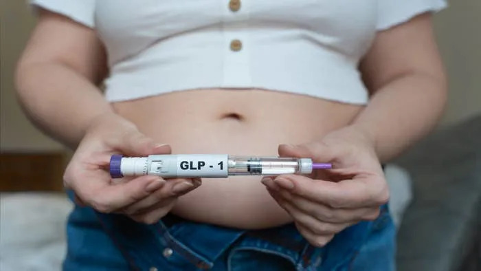 Person holding a GLP-1 medication pen, highlighting its relevance in health-related contexts, particularly in weight management and diabetes care
