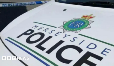 Stock shot of the bonnet of a Merseyside Police van, which is white. The text 'MERSEYSIDE POLICE' is seen on the front in black and blue lettering.