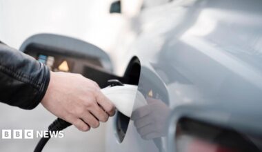 Person's hand putting a charger into an electric vehicle