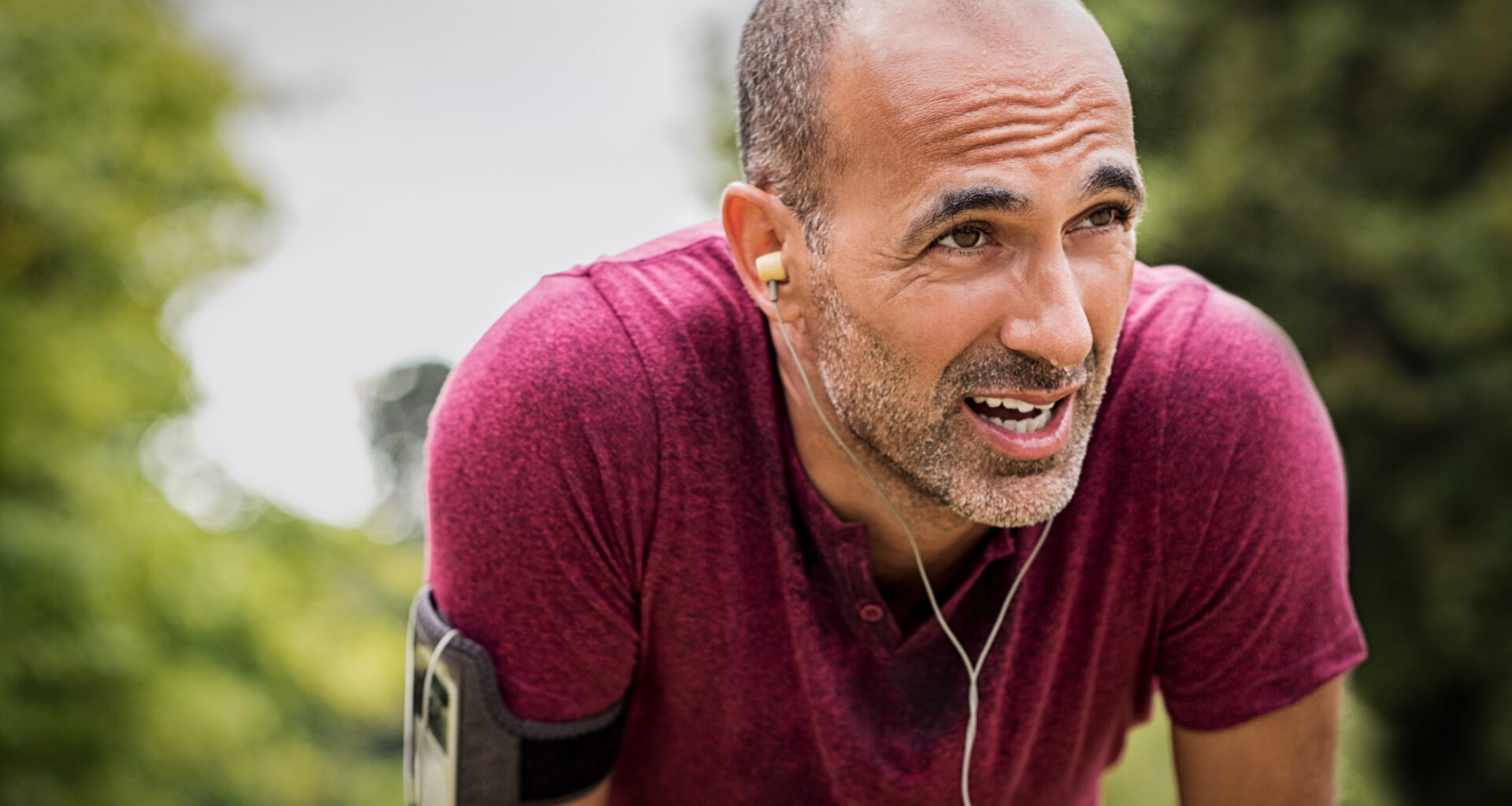 A senior man resting after jog at the park on a sunny day.