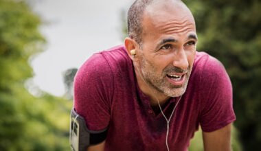 A senior man resting after jog at the park on a sunny day.