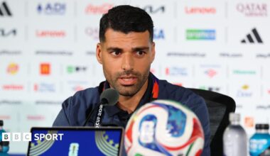Mehdi Taremi speaks into a microphone while conducting a press conference
