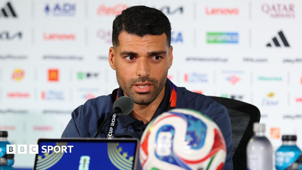 Mehdi Taremi speaks into a microphone while conducting a press conference