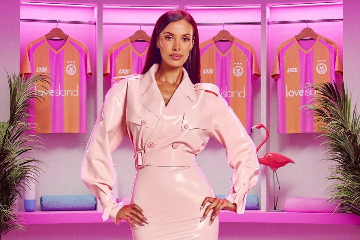 An individual is standing confidently in front of a vibrant pink backdrop, adorned in a striking pink outfit, with various pink garments displayed in the background.
