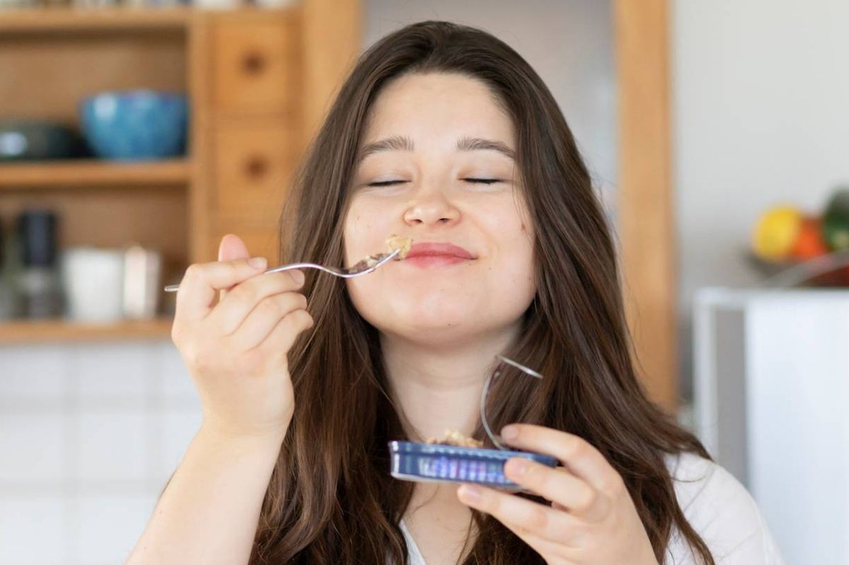 Woman eating sardines from a tin