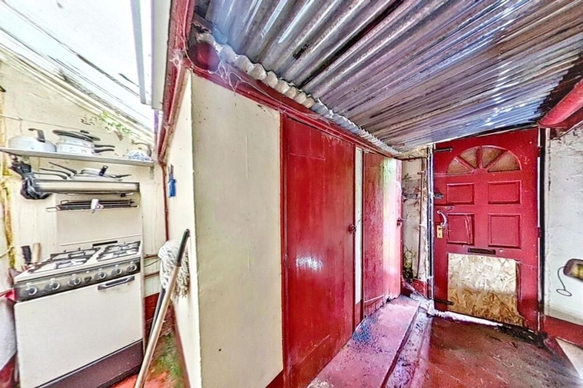 Red door opening into a space with a cook - very quirky - at the Last house on the streets of village of Troedrhiwfuwch going to auction with guide price of £35k plus with Paul Fosh Auctions