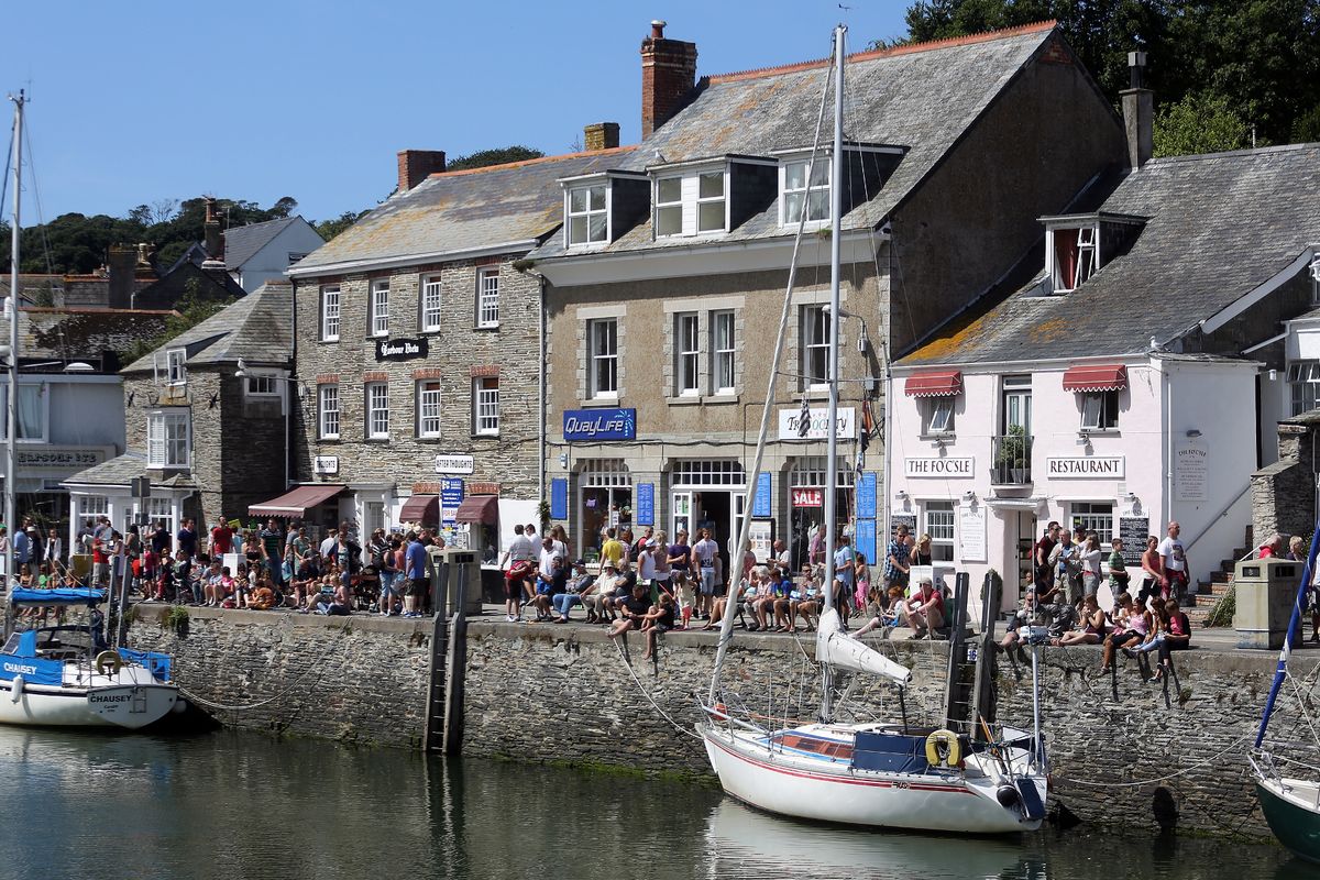  People sit on the harbour wall in Padstow